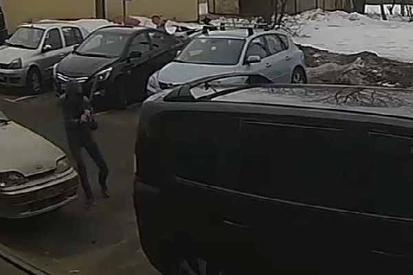 Мужчина разбивает фары автомобиля. Кадр записи с камеры видеонаблюдения